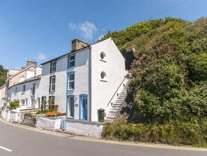 A white building with blue accents, a staircase leading to the entrance, and a road in front.