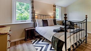 A bedroom with a bed, two windows, a small bedside table, a nightstand, a patterned rug, and a ceiling light. - 3 Bed in Sturminster Newton (oc-rcorn) (Sturminster Newton)