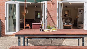 An outdoor patio with a wooden table, a green umbrella, and a brick wall. - 3 Bed in Sturminster Newton (oc-rcorn) (Sturminster Newton)
