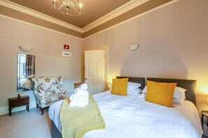 A hotel room with a bed, a chair, a mirror, and a door. - 1 Bed in Harrogate (oc-hh055) (Harrogate)