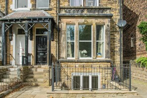 A traditional stone building with a front entrance, a small porch, and a metal fence. - 1 Bed in Harrogate (oc-hh055) (Harrogate)