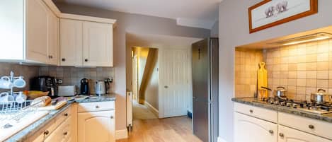 A kitchen with white cabinets, a stainless steel refrigerator, a gas stove, and a coffee maker.