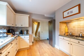A kitchen with white cabinets, a stainless steel refrigerator, a gas stove, and a coffee maker. - 1 Bed in Harrogate (oc-hh055) (Harrogate)