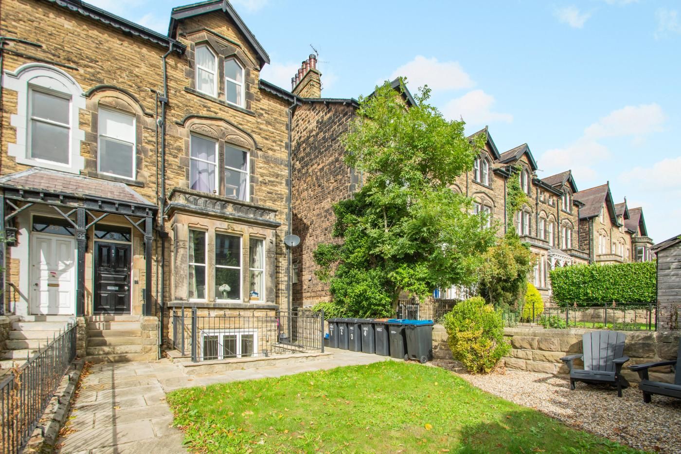 A row of terraced houses with a grassy front yard and a tree.