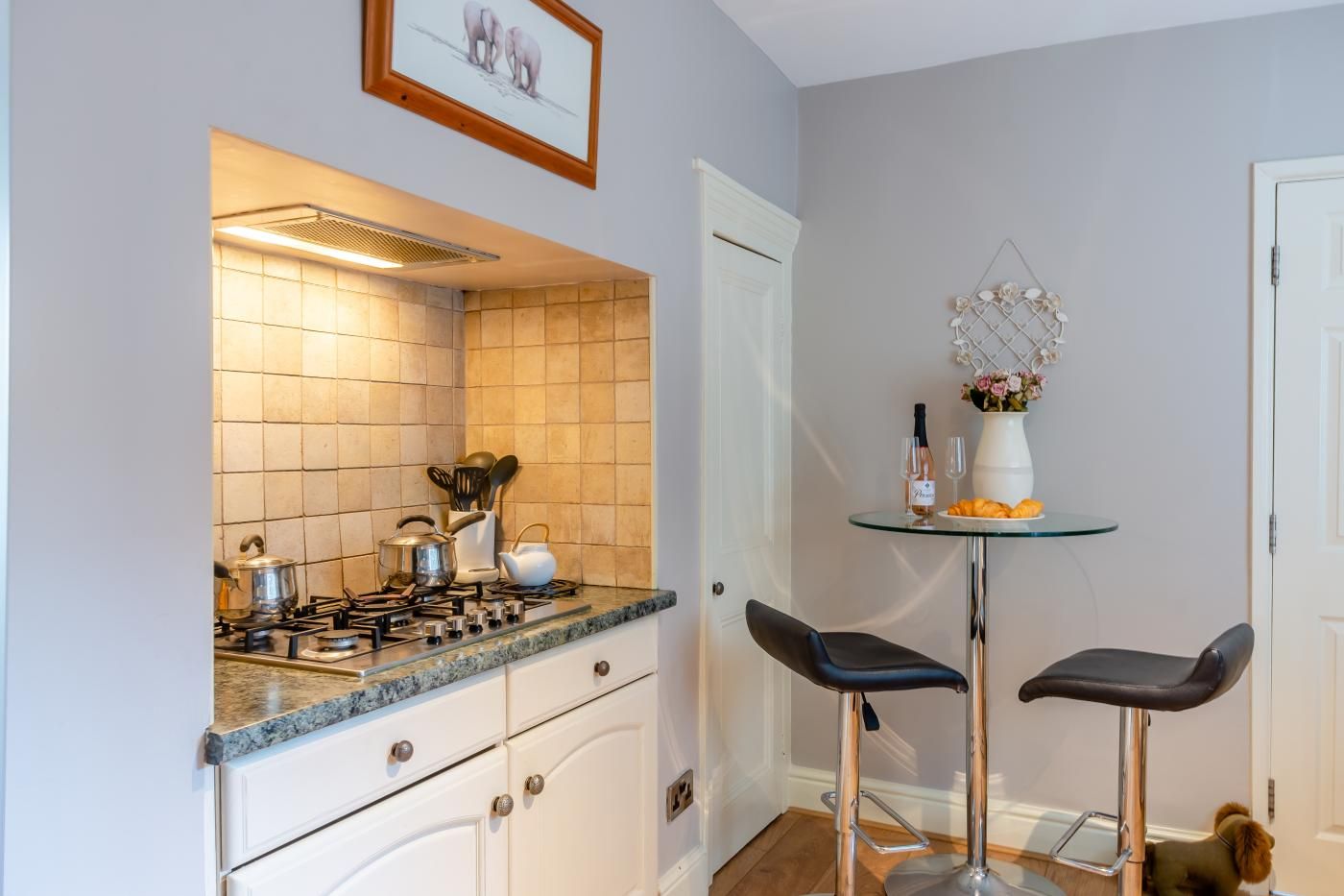 Una cocina con estufa a gas, un lavamanos y un pequeño comedor con dos sillas y una mesa.
