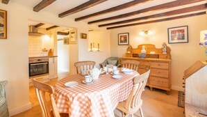 A dining area with a checkered tablecloth, wooden chairs, and a wooden cabinet with a mirror. - 2 Bed in Northallerton (oc-g0172) (Thimbleby)