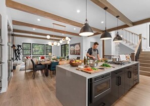 A modern kitchen with a central island, pendant lighting, and a staircase leading to an upper level. - The Riverstone | Luxury Alcove • Kindred • Ski-In/Out • Spa • Heated Garage (Keystone)