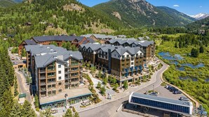 A multi-story hotel with a central courtyard, surrounded by mountains and a lake. - The Riverstone | Luxury Alcove • Kindred • Ski-In/Out • Spa • Heated Garage (Keystone)