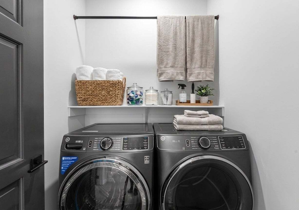 A laundry area with two washing machines, a basket of towels, and a shelf with toiletries.