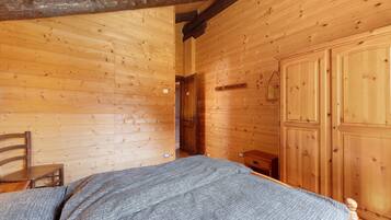 Una habitación de madera con cama, una silla y un armario.
