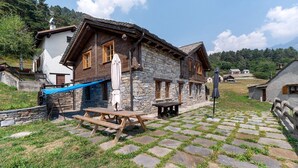 A traditional stone building with a wooden exterior, a covered outdoor seating area, and a stone-paved courtyard.