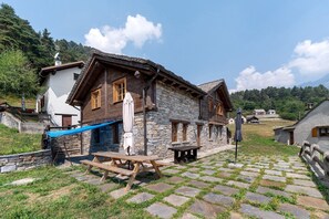 A traditional stone building with a wooden exterior, a covered outdoor seating area, and a stone-paved courtyard.