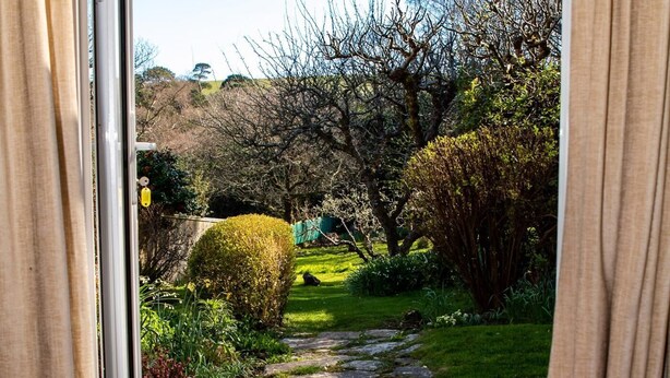 A stone pathway leading through a garden with various shrubs and trees. - 2 Bed in Swanage (oc-dc069) (Studland)