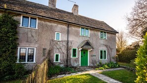 A two-story house with a green door, white-framed windows, and a stone pathway leading to the entrance. - 2 Bed in Swanage (oc-dc069) (Studland)