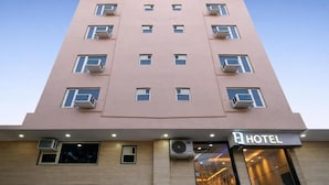 A multi-story hotel building with a flat facade, air conditioning units, and a visible entrance with a sign. - Hotel Urban Tree At Delhi Airport (New Delhi)