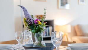A dining table set with plates, glasses, and a vase of flowers. - 2 Bed in Bideford (oc-oce16) (Westward Ho!)