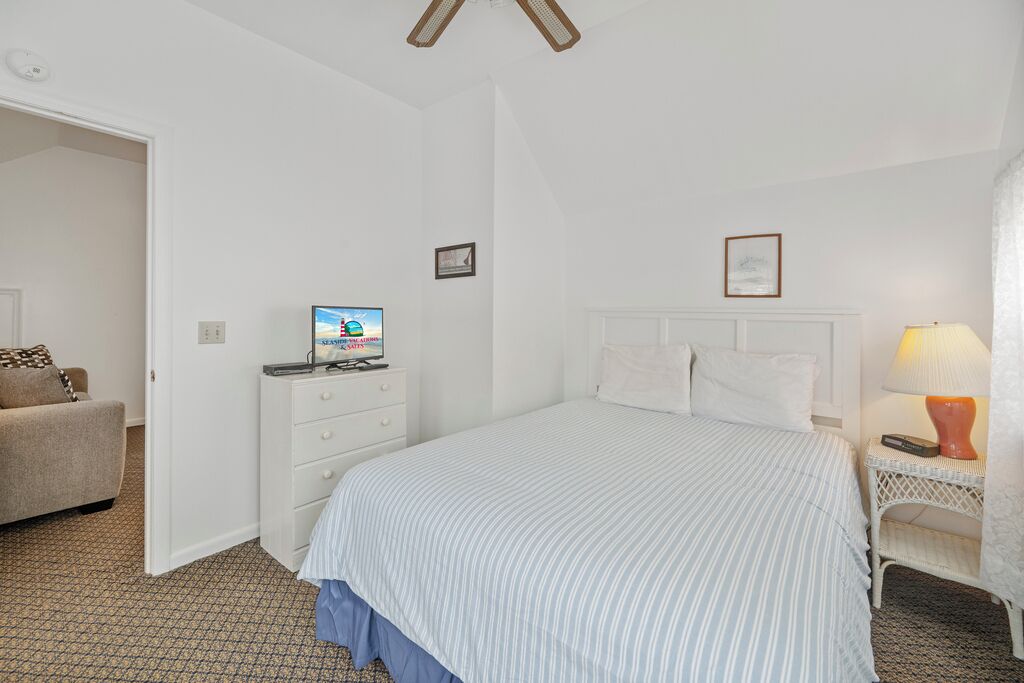 Ein Schlafzimmer mit einem Bett, einem Schminktisch, einem Fernseher und einem Sessel.