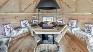 Ein gemütliches Blockhaus-Interieur mit Kamin, Holzwänden und geneigter Decke.