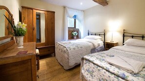 A bedroom with two beds, a wooden wardrobe, a dresser, a mirror, and a window with curtains. - 3 Bed in Buxton (oc-pk656) (Blackwell)