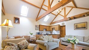 A spacious living area with wooden beams, a dining table, and a kitchen in the background. - 3 Bed in Buxton (oc-pk656) (Blackwell)