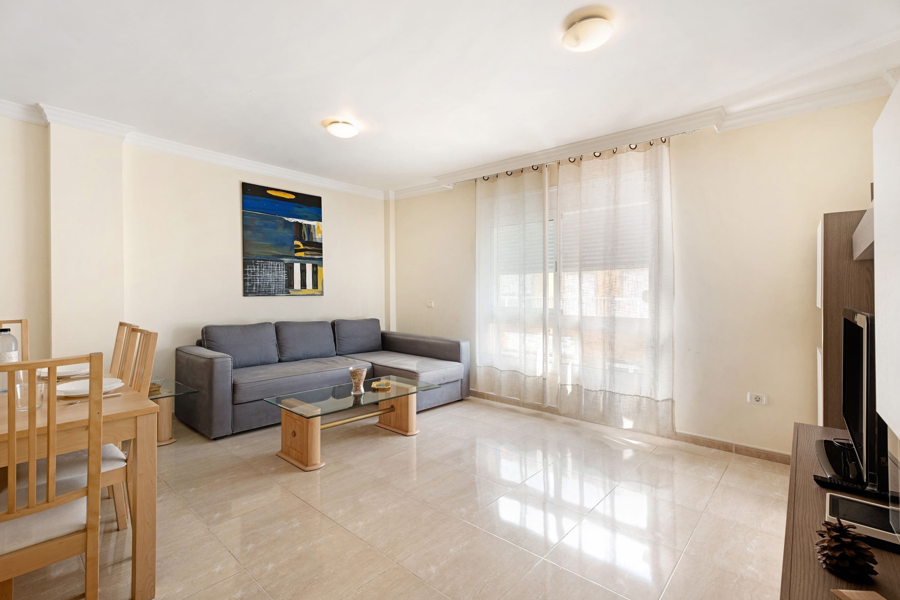 A modern living room with a sofa, coffee table, and TV stand.
