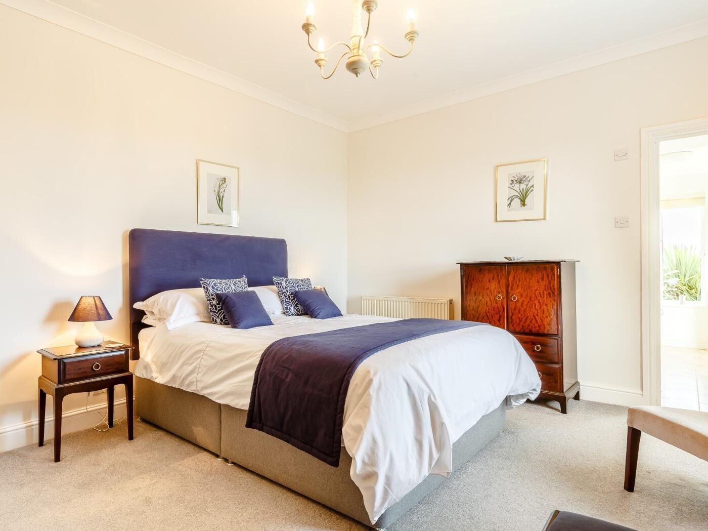 A bedroom with a bed, a nightstand, a dresser, and a chandelier.