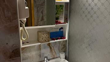 A bathroom with a marble sink, a mirror, shelves with toiletries, and a shower curtain with a geometric pattern.