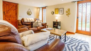 A cozy living room with leather sofas, a fireplace, and a view through large sliding doors. - 2 Bed in Holsworthy (oc-gmead) (Holsworthy Hamlets)