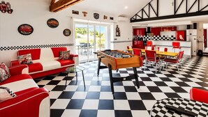 A room with a checkered floor, a foosball table, a red and white sofa, and a kitchen area with red cabinets. - Two charming vacation rentals in a beautiful setting, accommodating up to 12 people (Clévilliers)