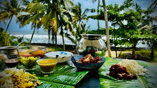 Comida sobre una mesa con vista al océano y palmeras.