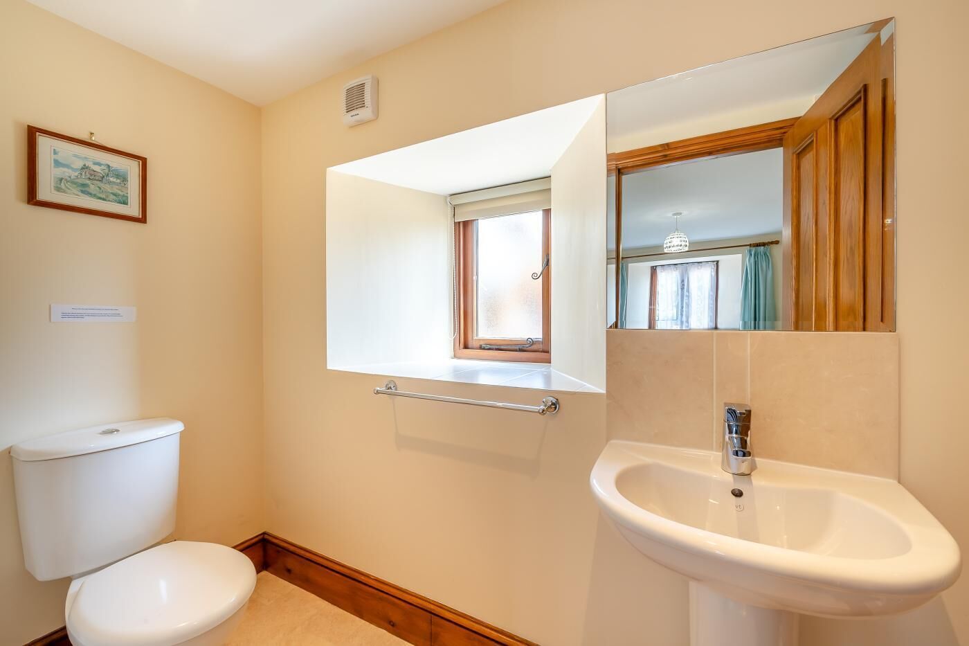 A bathroom with a toilet, a sink, and a mirror.