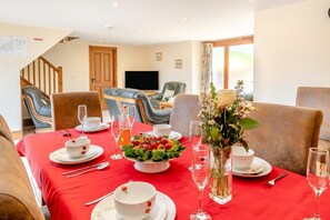 A dining area with a red tablecloth, set for a meal with plates, glasses, and a centerpiece of flowers.
