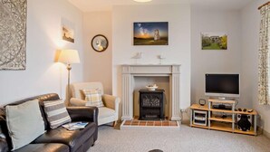 A living room with a sofa, armchair, fireplace, television, and decorative wall art. - 3 Bed in Niton Undercliff (oc-ic125) (Niton)