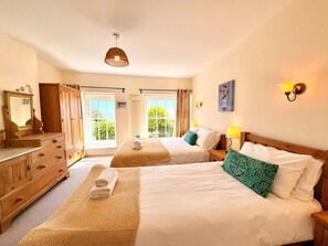 Ein Hotelzimmer mit zwei Betten, einem Holzschrank, einem Spiegel und Blick ins Grüne.