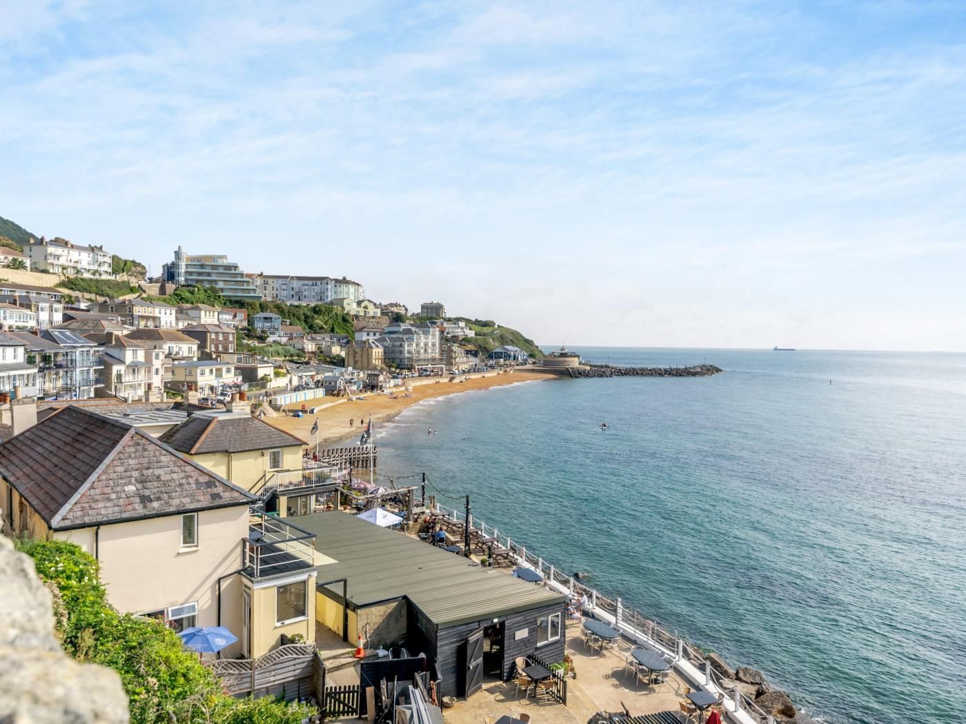 A coastal town with a beach, buildings, and a pier.