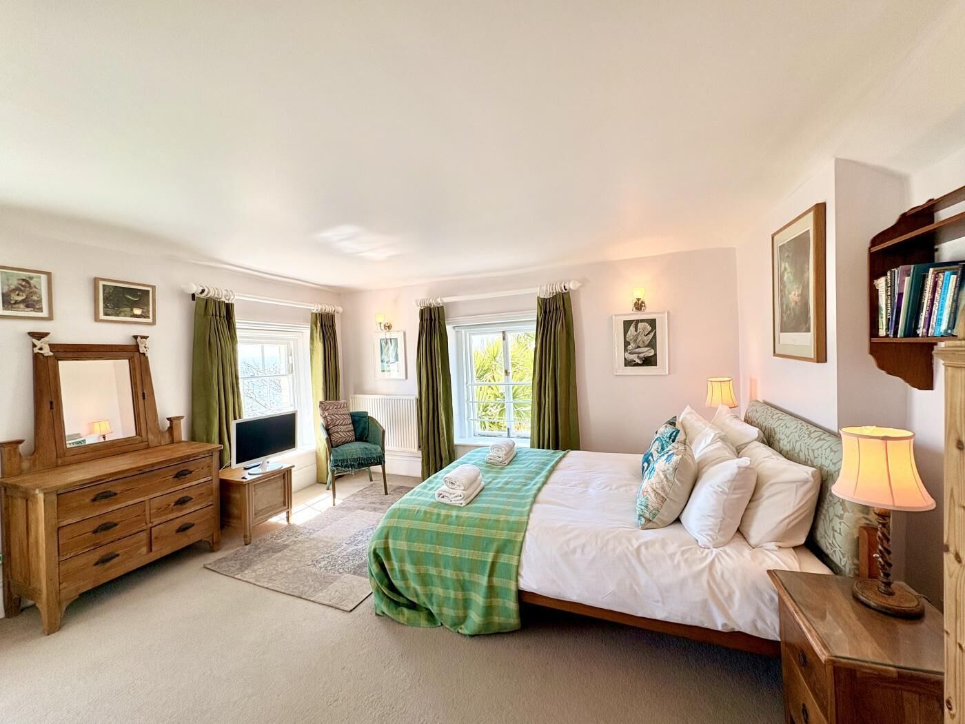 A bedroom with a bed, dresser, chair, bedside table, and a bookshelf.