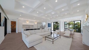 A spacious living area with a sectional sofa, a glass coffee table, and a dining area with chairs. - Sunset Tulia Paradise (Anna Maria)