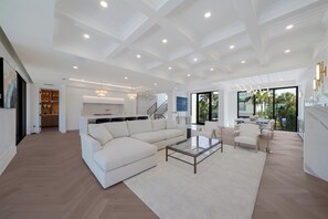 A spacious living area with a sectional sofa, a glass coffee table, and a dining area with chairs. - Sunset Tulia Paradise (Anna Maria)