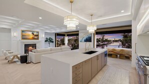 A modern kitchen with a large island, pendant lighting, and a view of a waterfront. - Sunset Tulia Paradise (Anna Maria)