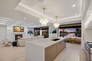 A modern kitchen with a large island, pendant lighting, and a view of a waterfront. - Sunset Tulia Paradise (Anna Maria)