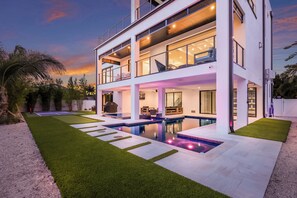 A modern two-story house with a swimming pool, outdoor seating, and a well-maintained lawn. - Sunset Tulia Paradise (Anna Maria)