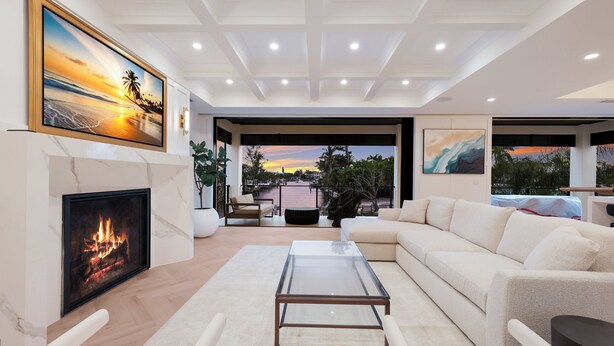 A modern living room with a fireplace, a glass coffee table, a sofa, and a view of the outdoors. - Sunset Tulia Paradise (Anna Maria)