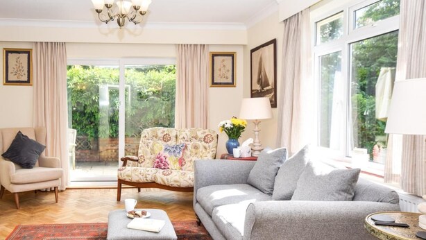 Un salon comprenant un canapé, un fauteuil, un pouf et un tapis à motifs.
