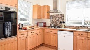 Une cuisine moderne avec des meubles en bois, un four encastré, un four à micro-ondes et un lave-vaisselle.