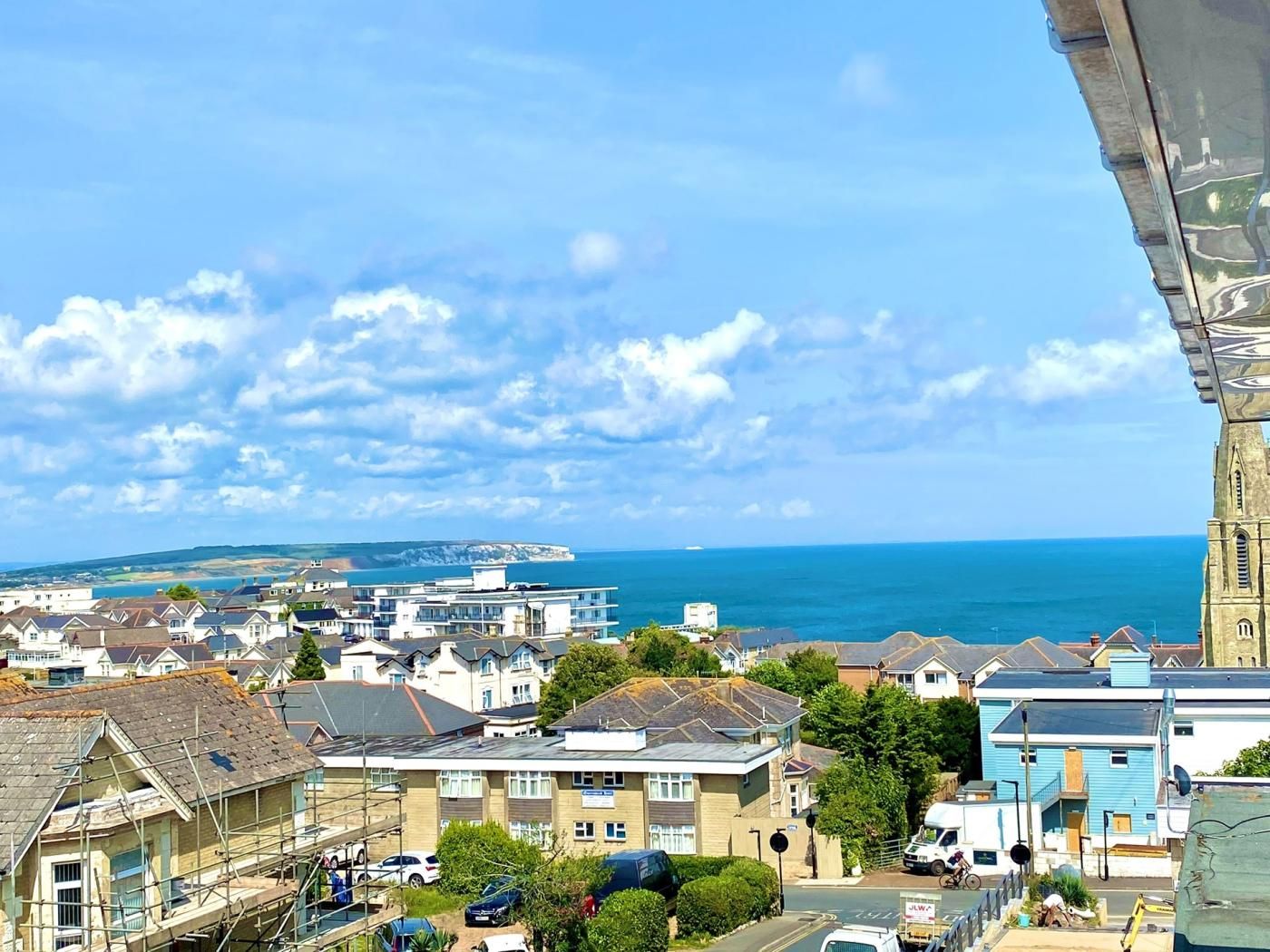 A coastal town with buildings, a clear sky, and the sea in the background.