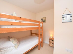 Une chambre avec un lit superposé, une échelle en bois, une table de chevet avec une lampe et un tableau accroché au mur.
