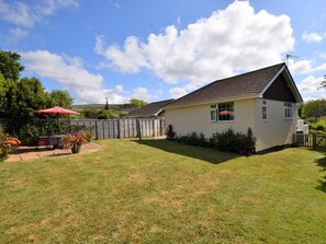 A single-story house with a tiled roof, a fenced backyard, and a red umbrella. - 2 Bed in Brighstone (oc-ic132) (Brighstone)