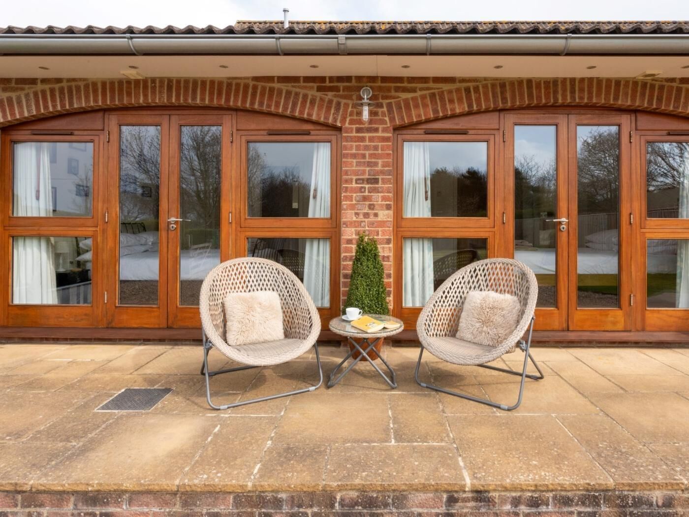 A covered patio with two wicker chairs, a small table, and a potted plant.