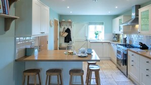 A kitchen with a central island, stools, a stove, and cabinets. - 4 Bed in Bembridge (oc-ic130) (Hillway)