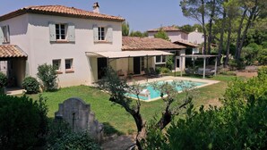 Une maison à deux étages avec une piscine, un espace salon extérieur et un jardin.